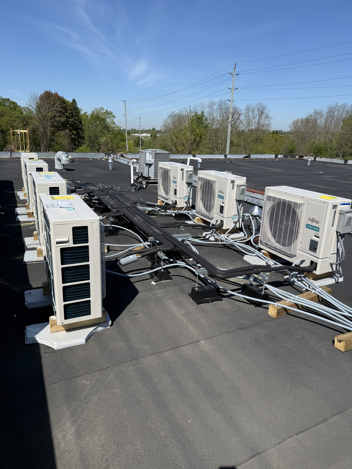 Finished rows of heat pump condensing units with line sets connected, blue sky above