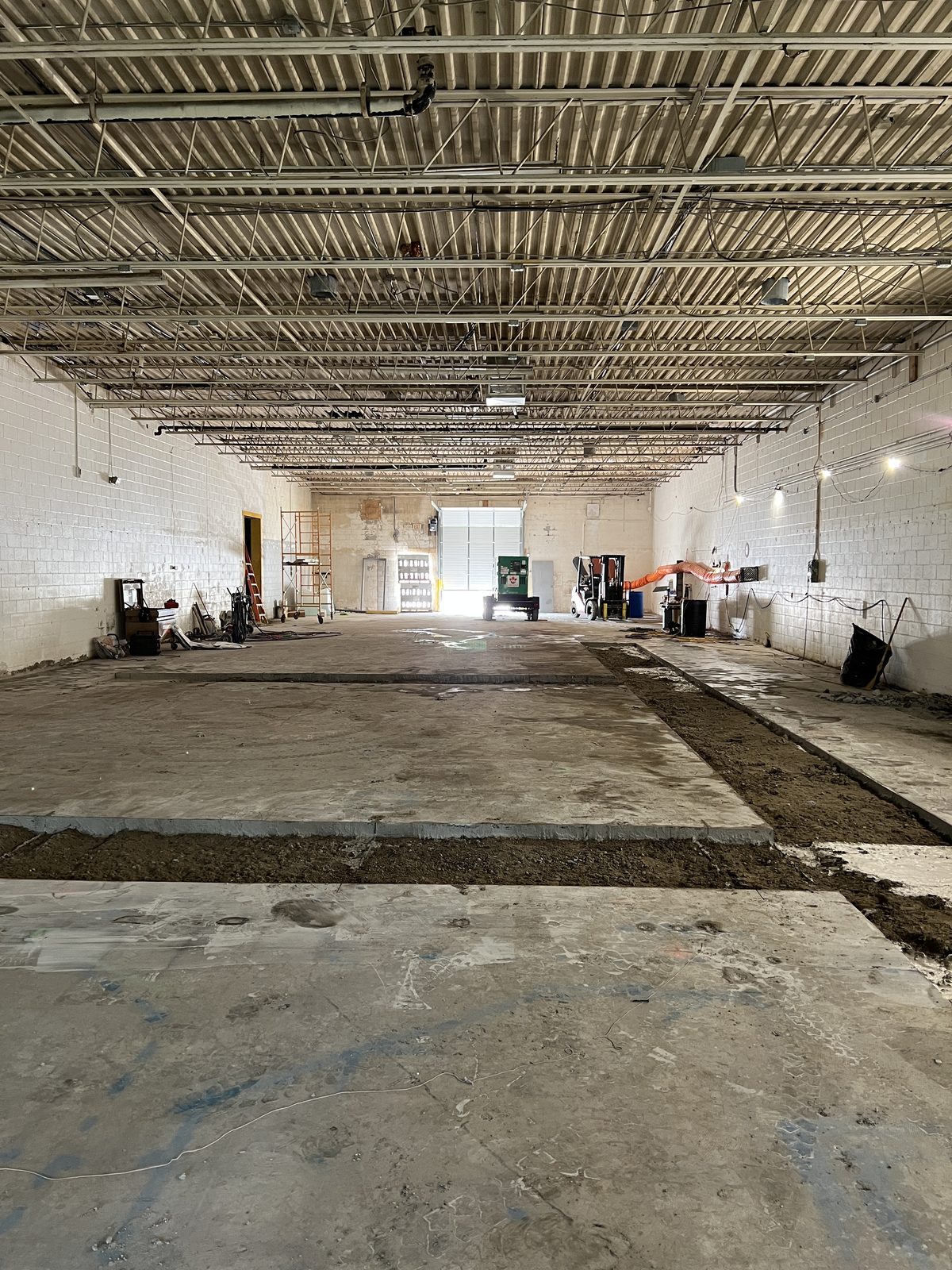 Warehouse floor with the concrete slab cut and lifted along the drain routes