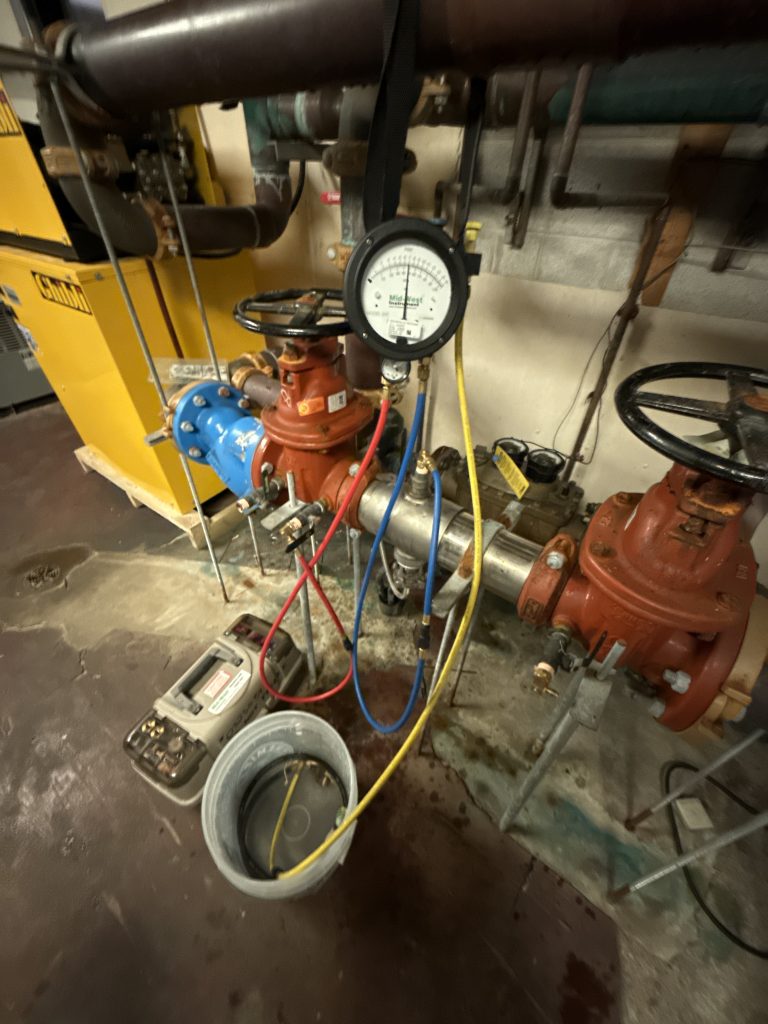 Backflow prevention device with test gauge setup during inspection in a commercial mechanical room by Spec-Mark Group