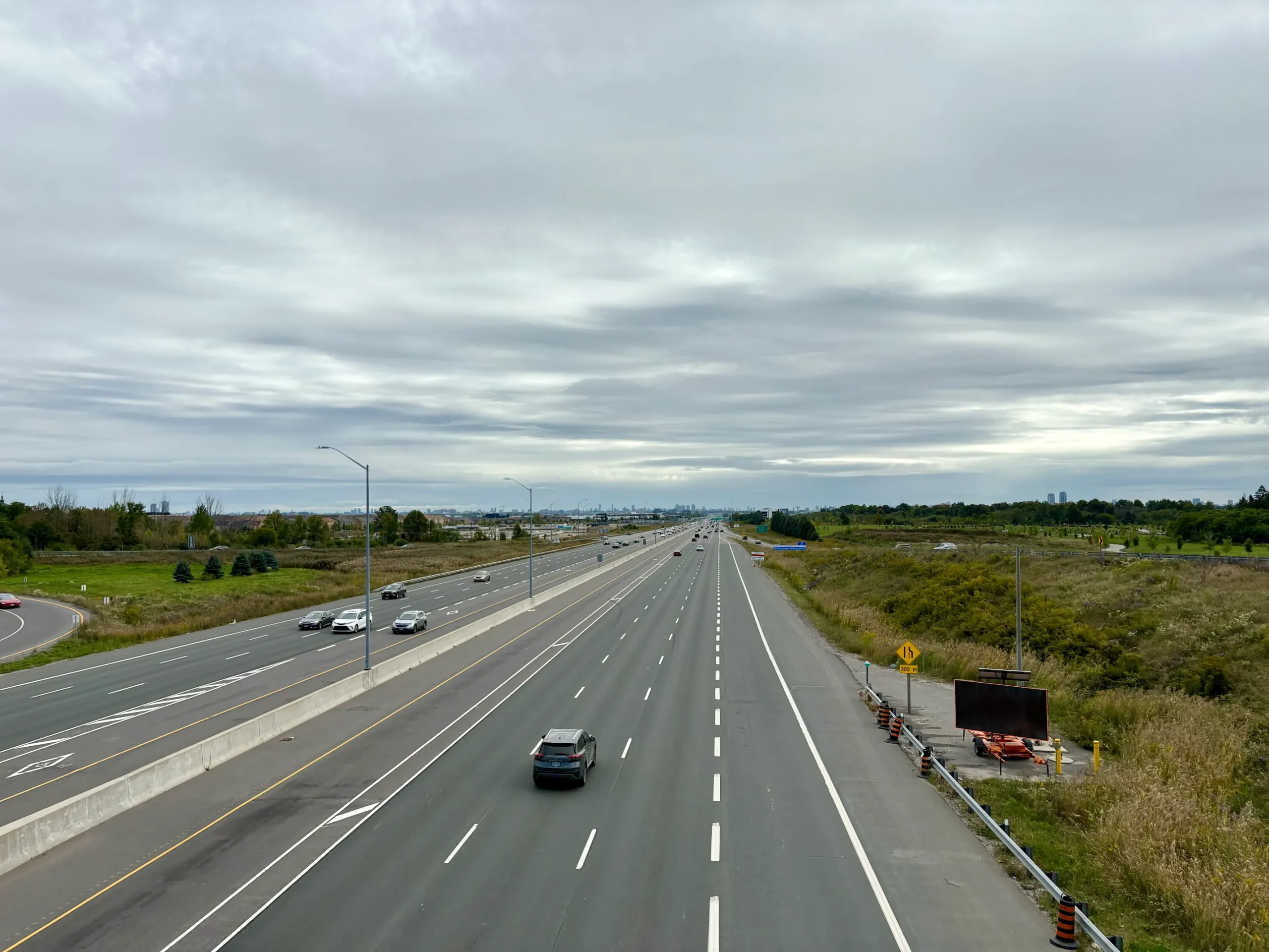 Wide view of Highway 404 northbound near Toronto with light traffic under overcast skies, through the Dixie Industrial Area
