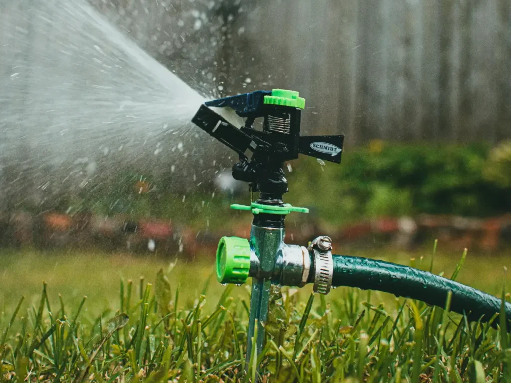 Oscillating garden sprinkler watering green lawn in backyard