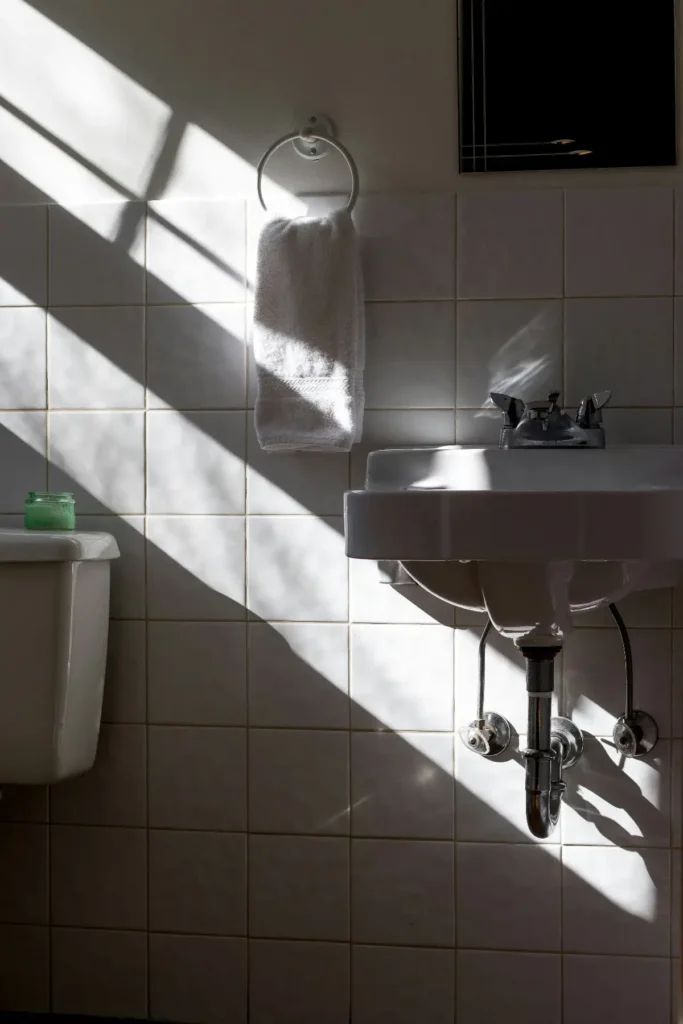 Minimalist bathroom sink with towel and natural sunlight